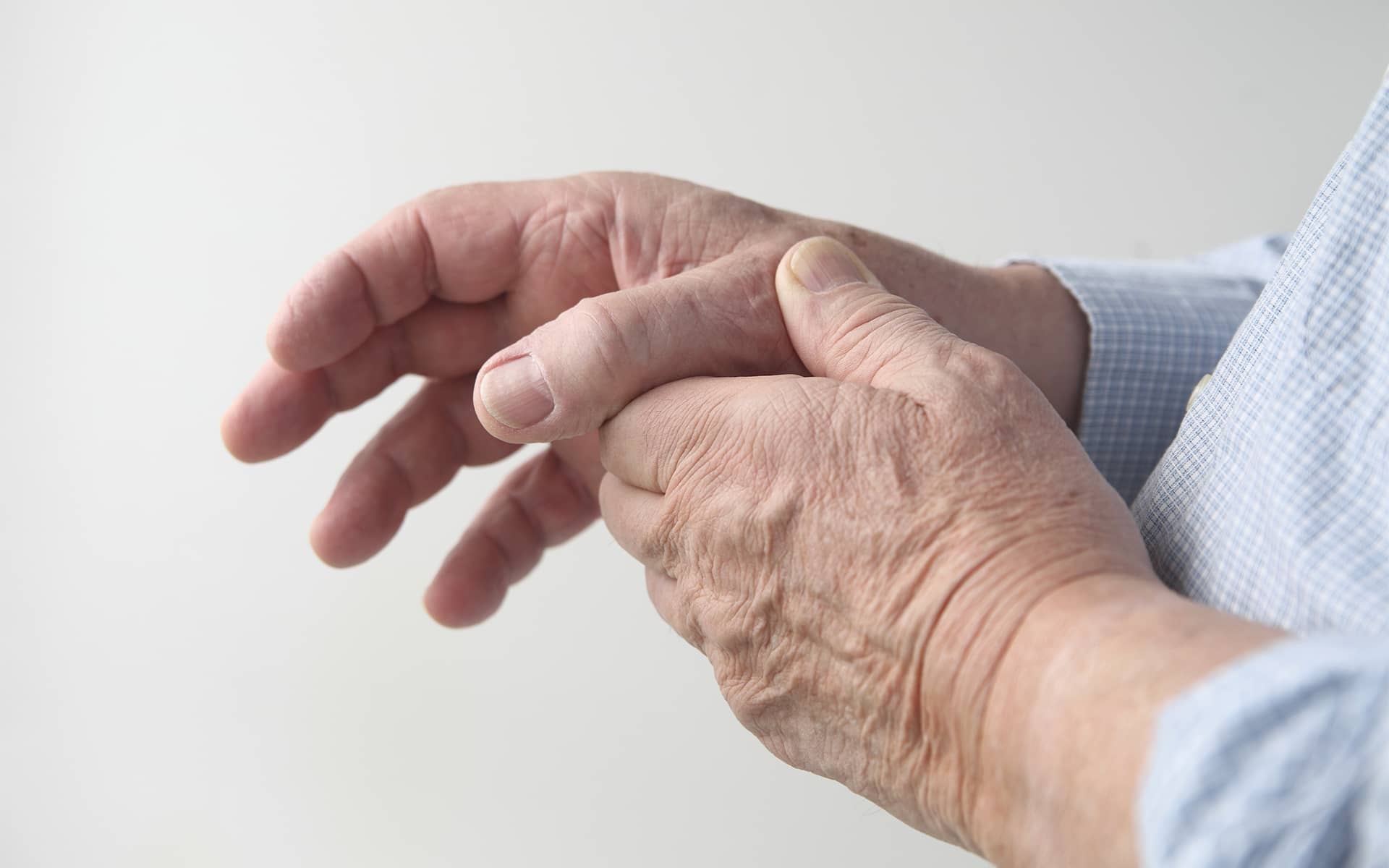 Mains d'un homme âgé se tenant le pouce en signe de rhizarthrose