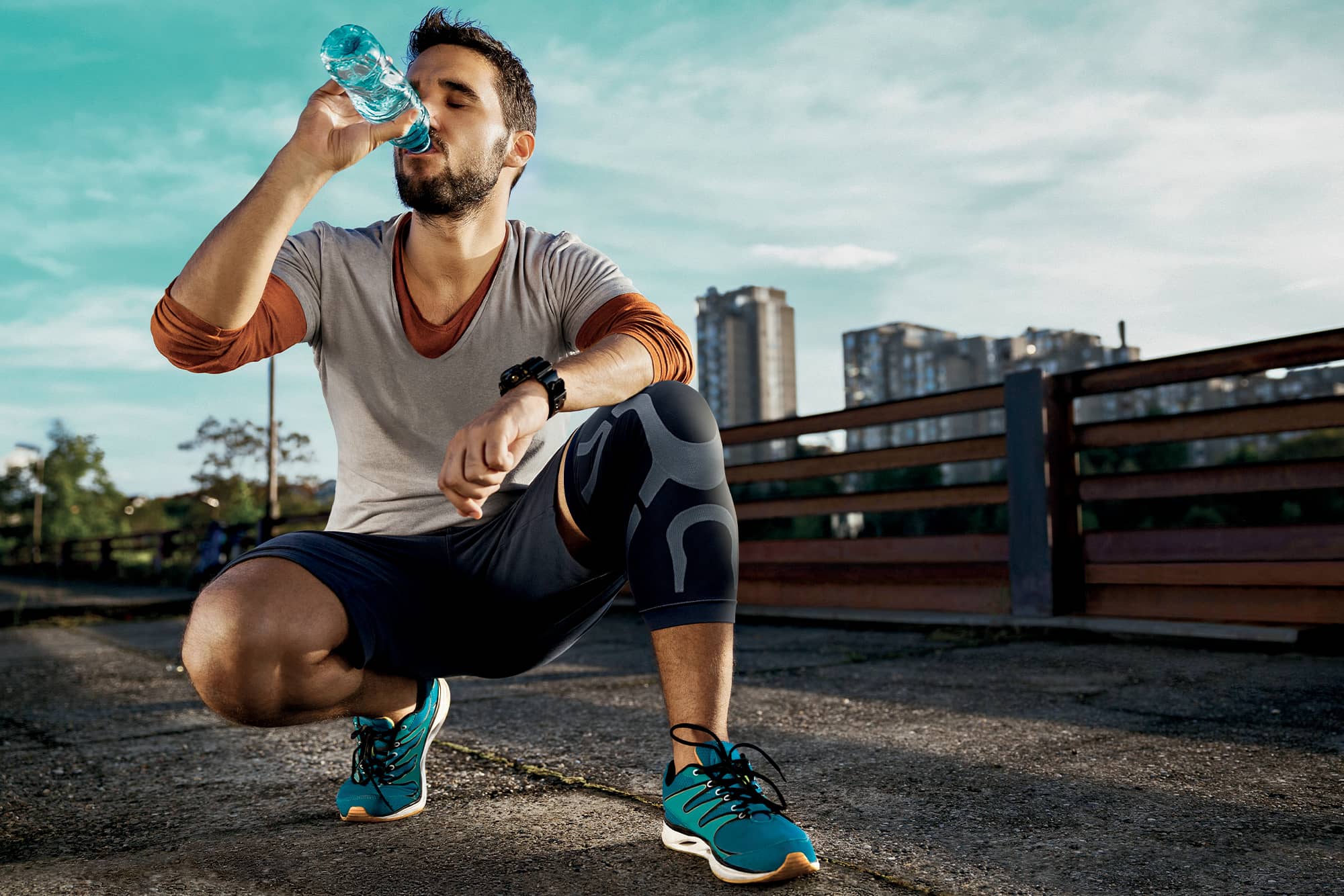 sportif buvant de l'eau et portant la genouillère skintape orliman