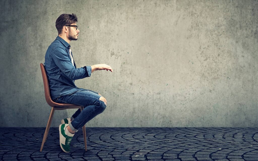 homme assis sur une chaise mimant le travail de bureau - posture dos