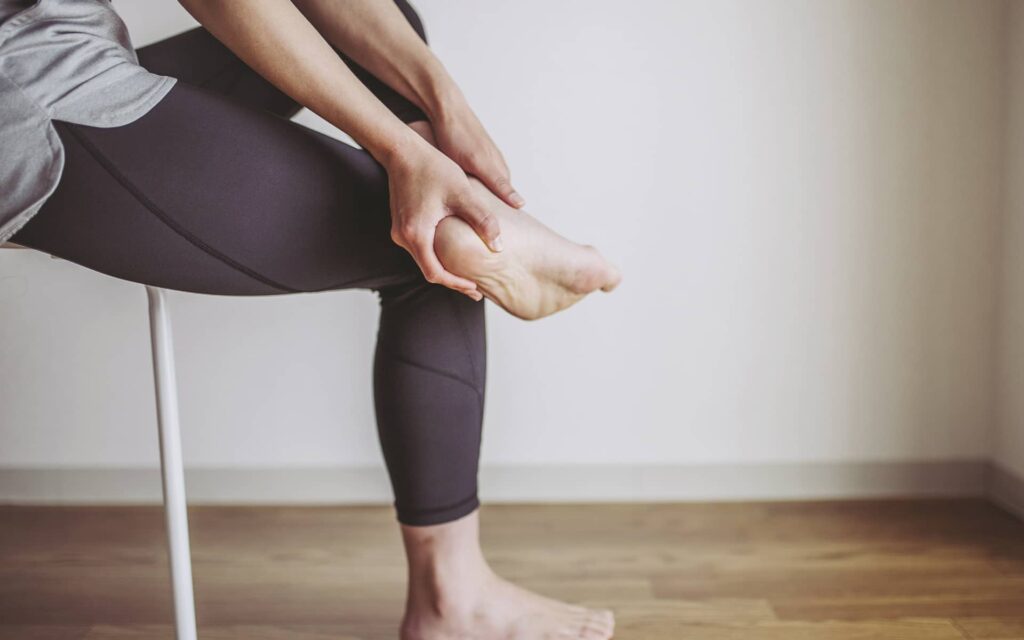 Femme assise en tenue de sport faisant des assouplissement de la cheville - steppage