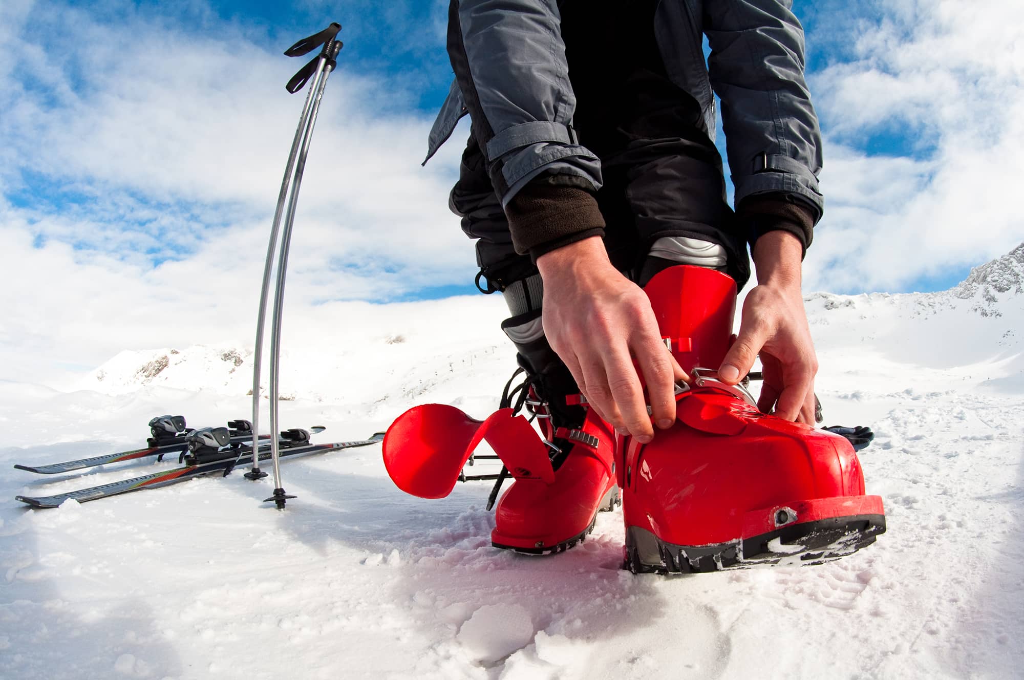Homme attachant ses chaussures de ski à la montagne