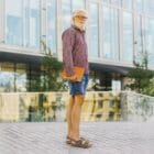 Sandales thérapeutiques CHUT modèle Coz Castel pour orteils en griffe et orteils en marteau, portée par un homme senior aux cheveux blancs en short jean et chemise à carreaux, debout devant un bâtiment moderne
