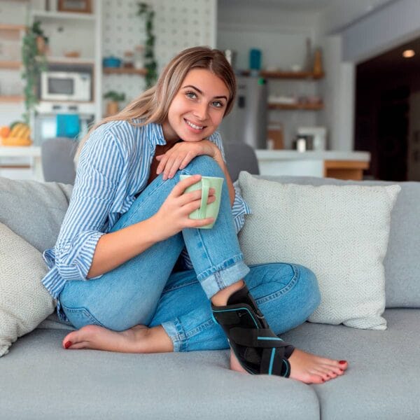 orliman-fixquick-max-attelle-cheville-sit-1200 Femme avec tase de thé sur son canapé et portant une attelle de cheville Fixquick Max