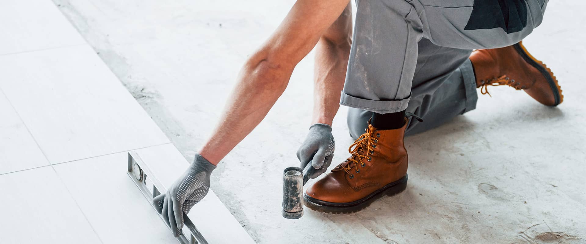 Carreleur agenouillé au travail, exposé au risque de développer un genou du sauteur ou une tendinopathie rotulienne