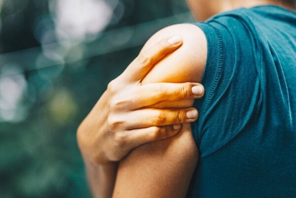 Personne touchant son épaule douloureuse, symptôme fréquent d’une rupture de la coiffe des rotateurs