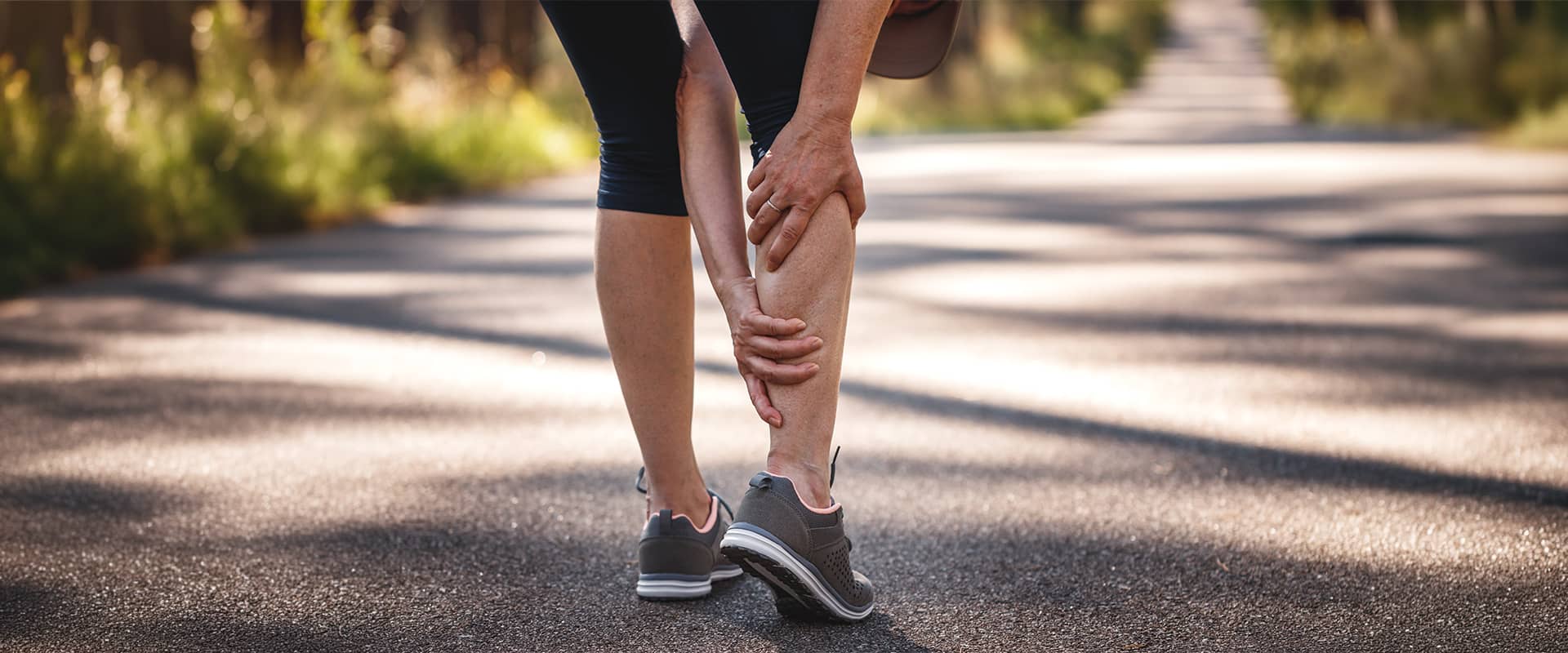 Coureuse souffrant d'une douleur au mollet pendant sa course, symptôme typique d'une lésion musculaire ou d'un claquage