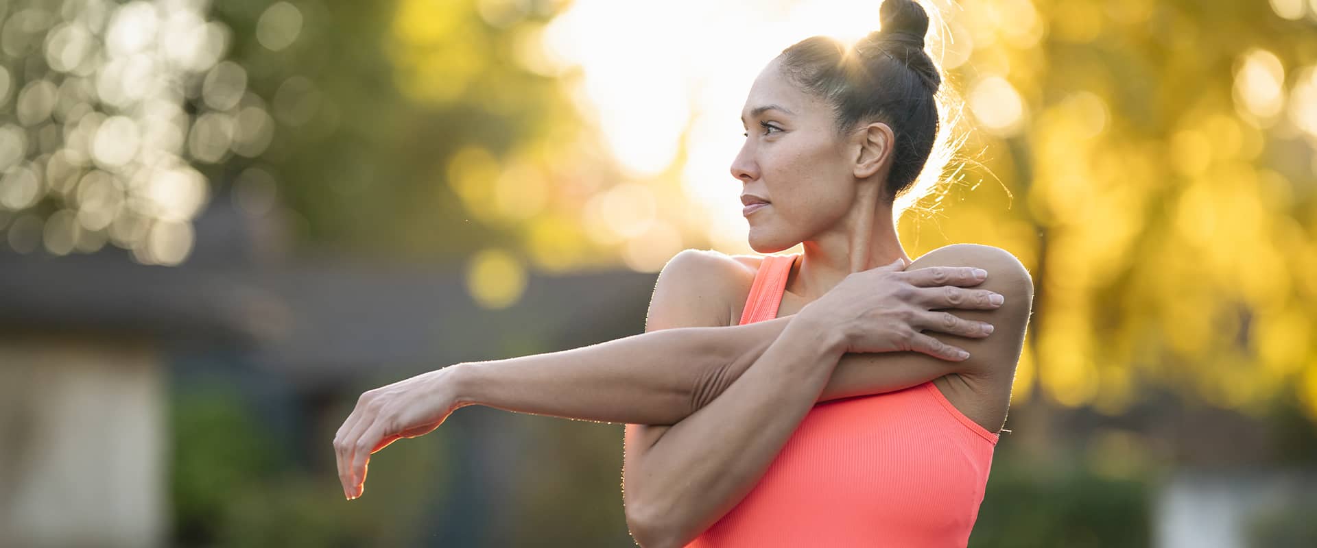 Sportive réalisant des étirements de l'épaule en extérieur pour prévenir les accidents musculaires avant l'effort