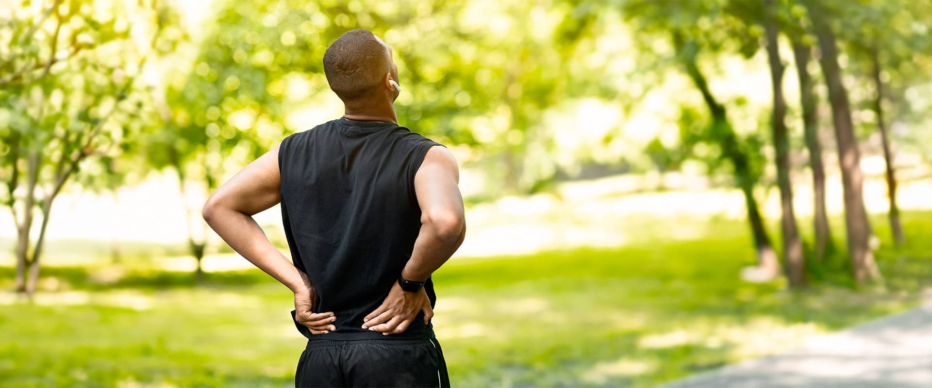 Sportif souffrant d'une douleur lombaire pendant sa séance en plein air, exemple de blessure musculaire à prévenir pour progresser sans se blesser