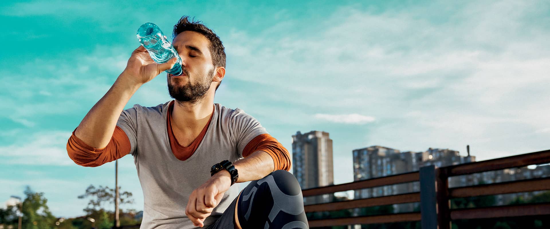 Sportif portant une genouillère de compression Orliman Skintape et s'hydratant après l'effort, pour optimiser la récupération et prévenir les blessures musculaires