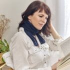 Femme en train de lire un livre et portant l’écharpe de thermothérapie Prim’Arthrose pour soulager les douleurs liées à l’arthrose cervicale débutante